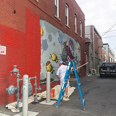 A man paints over a mural by Donald Ross, aka Scribe, in the Brady Arts District on July 14  