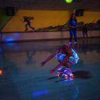 A skater ducks down low as she slides beneath the bar during the limbo competition held each night at Skateland.