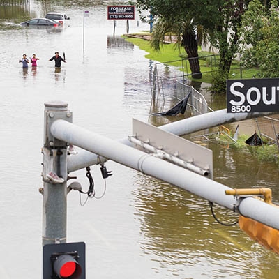 Houston residents walk across the flooded street in Houston, Texas, on August 27.