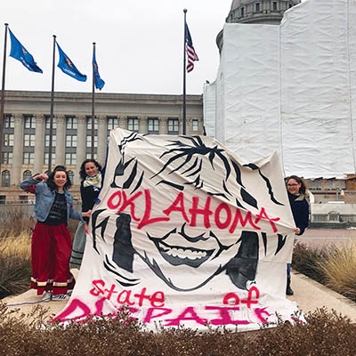 Sydne Gray, Ashley McCray, and Madison Lovell hold up their banner outside the State Capitol, Feb. 5