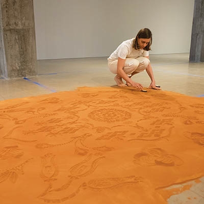 Rena Detrixhe working on her “Red Dirt Rug” at Philbrook Downtown in April