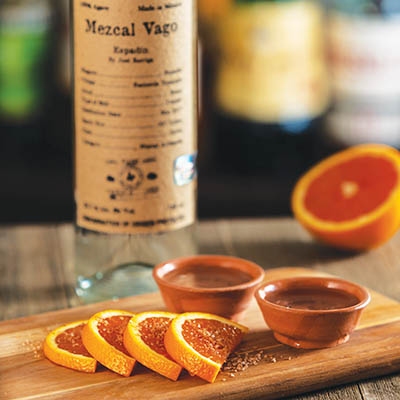 Mezcal served in traditional clay copitas with oranges and sal de gusano